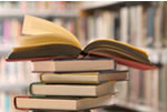 Photo of a stack of books.  Top book is open.